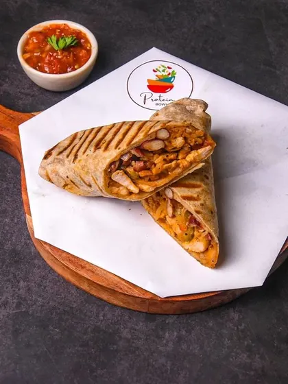 A Mexican-style wrap filled with grilled chicken, cut in half and served on a wooden platter with salsa.