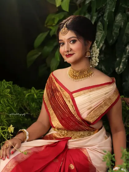 Portraits from a makeup shoot, showcasing a model in a classic red and cream saree. The images highlight the flawless makeup and traditional styling in a beautiful garden setting.