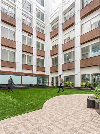 This view of the Sarvesh Health City courtyard shows people walking through the landscaped area. The space is not just a visual amenity but a functional part of the hospital, offering a place for movement and fresh air.
