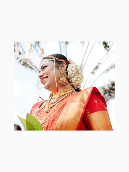 A joyful bride in her red silk saree, a candid shot capturing her beautiful smile.