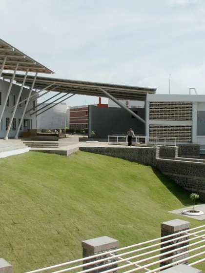 Landscaped mounds and open plazas at Symbiosis International University are designed to break the monotony of built forms. These green spaces provide areas for relaxation and social interaction, integrating nature into the daily life of the campus.