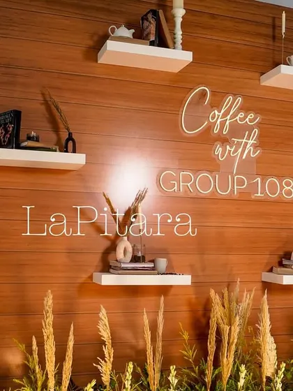 A closer look at the custom neon sign and styled shelves on our photo wall. The warm glow of the "Coffee with Group 108" sign added a modern touch to the rustic decor.