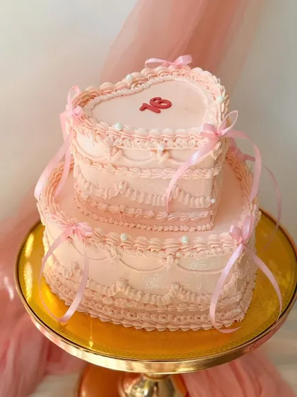 A spectacular two-tier heart-shaped cake with vintage Lambeth piping. This romantic design in soft pink is perfect for a sweet sixteen or a special anniversary.