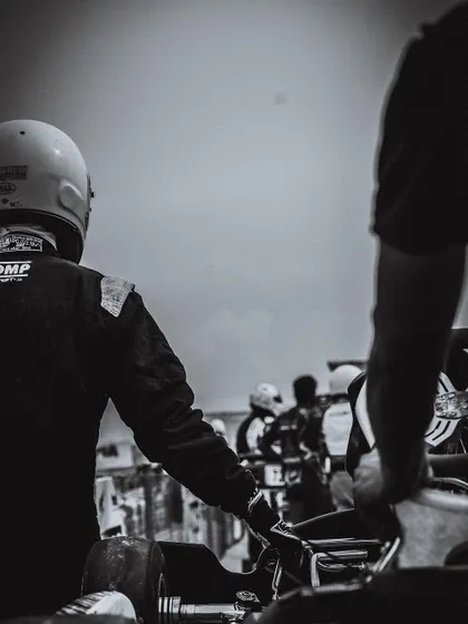 A black and white photo capturing a quiet moment of reflection for a driver before a race. The mental preparation is just as important as the physical.