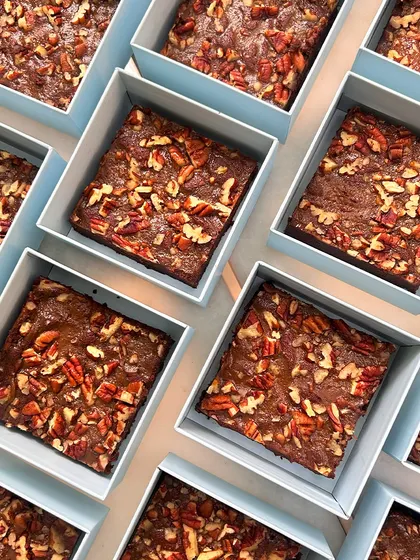 Rows of our fudgy pecan brownies, ready to be boxed up for a baby announcement bulk order. A rich and decadent treat to share with loved ones.