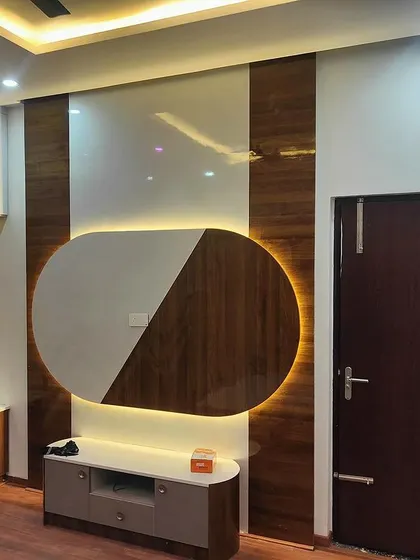 A bedroom featuring a unique TV unit with an oval backlit panel and a chevron-patterned wardrobe. This custom design demonstrates our ability to create artistic and functional statement pieces for any room.