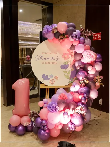 A beautiful welcome sign for Shanvi's 1st birthday. The floral design and the Rapunzel-inspired purple and pink balloon garland set the stage for the fairytale celebration inside.
