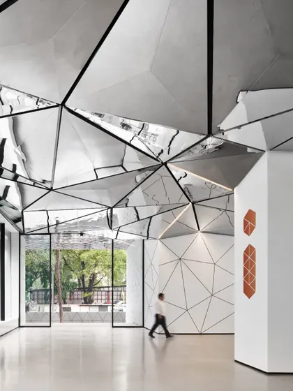 A person walking through the lobby provides a sense of scale, demonstrating how the architectural elements create a powerful human experience. The design connects the entrance to the core, guiding visitors through a visually rich environment.
