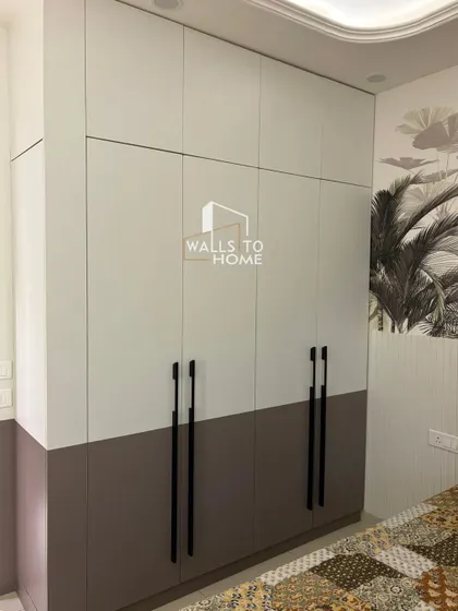 A close-up of a two-tone wardrobe with sleek black handles. This design adds a modern touch to the bedroom while providing ample storage.