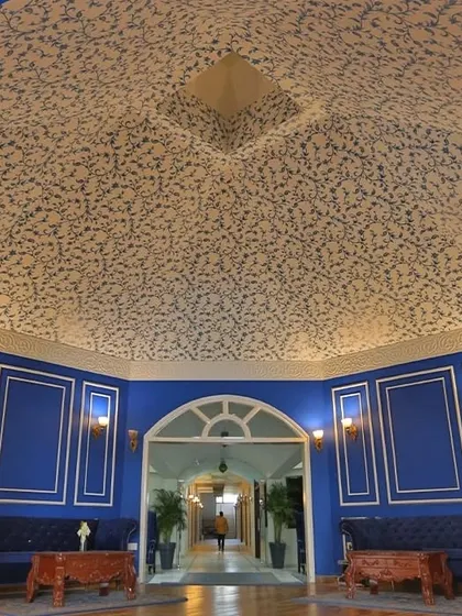 A wider view of the Mughal-inspired ceiling wallpaper, showing how it covers the expansive, curved ceiling to create a truly immersive and grand entrance for the hotel.