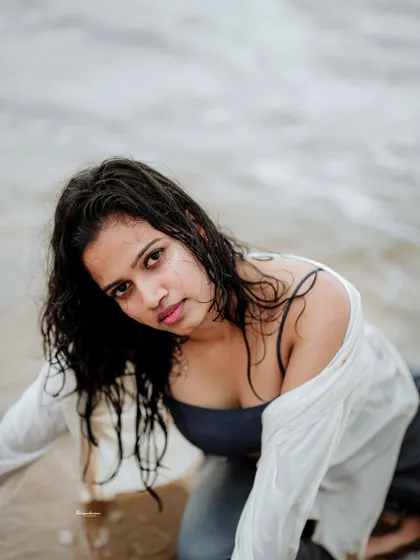 A close-up portrait in the water, focusing on the model's direct gaze. The wet look adds a sensual and natural element to the shot.