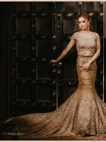 A full-length portrait of the bride in her glamorous golden gown, looking elegant and poised.