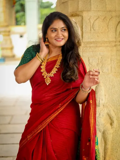 A happy, breezy shot that captures the beauty of the red saree. The makeup is light and fresh, enhancing her natural smile and creating a look of effortless grace.