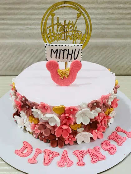 A sweet and simple cake bordered with a wreath of tiny, colorful handmade flowers, topped with a cute pink bow.