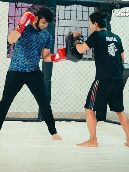 A student receives one-on-one instruction during a personal training session, working on his boxing combinations with a coach holding focus mitts.