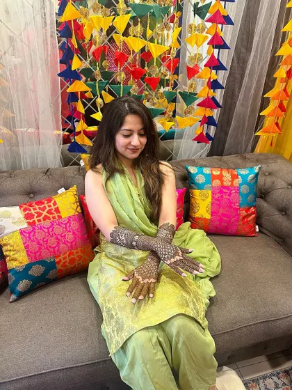 A serene shot of the bride amidst vibrant decor, her detailed mehndi complete.