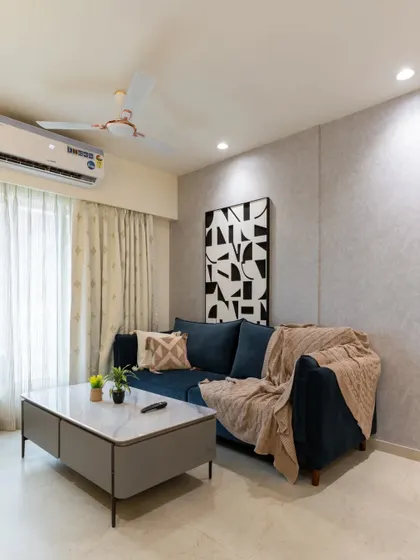 A cozy living room setup from our NESTA range, with a plush navy blue sofa, a minimalist coffee table, and abstract art creating a comfortable and stylish space.