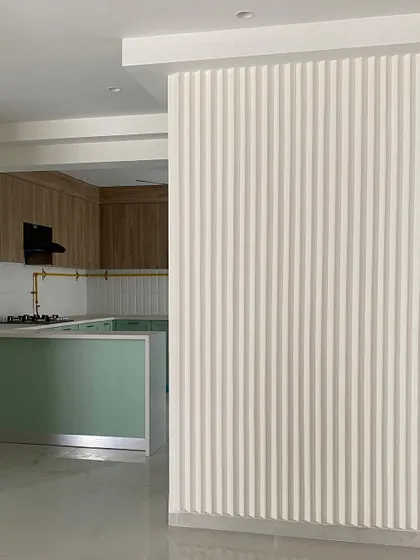 A view of the pistachio kitchen from the living area, showing the fluted paneling on the partition wall that cleverly separates the spaces.
