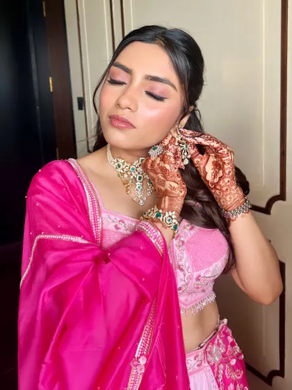 A beautiful candid shot showing the final touches. The soft pink eyeshadow and glowing cheeks are perfect for a romantic engagement ceremony.