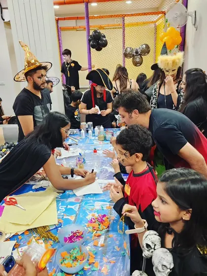 A table full of kids and parents working together on 'Ghostly Glow Jars'. I love providing activities that the whole family can enjoy side by side.