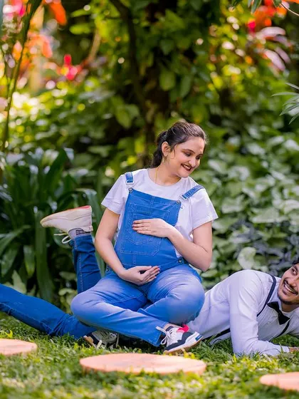 Maternity shoots can also be fun and casual. This couple opted for denim overalls and a relaxed pose on the grass, resulting in a playful and natural portrait that captures their happy, easygoing vibe.