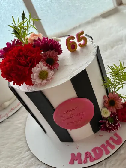 A closer look at the modern striped cake with a vibrant floral arrangement. A very stylish way to celebrate turning 65.