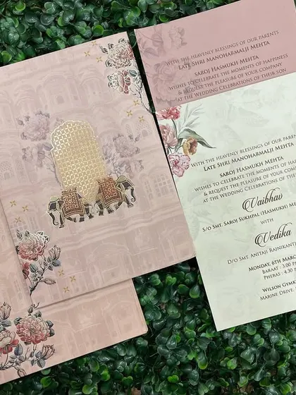 A beautiful invitation in pastel pink with traditional 'palki' and elephant motifs. The floral borders add a touch of softness to the design.
