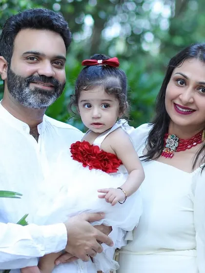 A classic family portrait taken during an outdoor session. The coordinated white outfits look fresh and timeless against the lush green background.