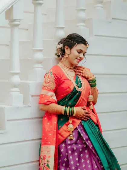 A serene portrait of the bride against a white staircase, highlighting the beautiful colors and details of her traditional attire.