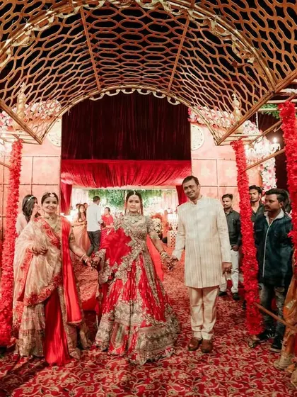 The bride's entry with her parents, walking down a carpet of red under a golden lattice archway. I ensure these family moments are as grand as they are emotional.