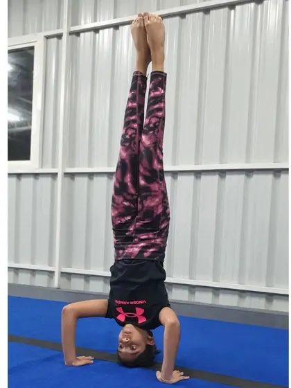 A clean and steady tripod headstand, demonstrating the strength and control required to balance upside down.