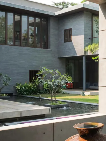 A serene water body wraps around the living spaces, reflecting the building and the sky, and creating a cool microclimate.
