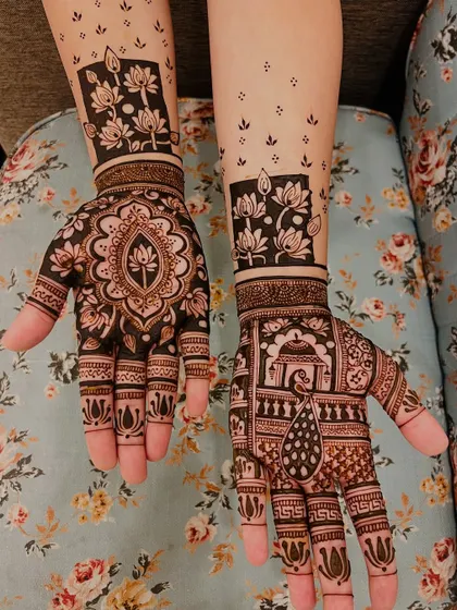 This design combines a central lotus mandala on one hand with a pictorial scene on the other, featuring a peacock and a domed structure. The lotus block pattern on the wrist is a modern touch.