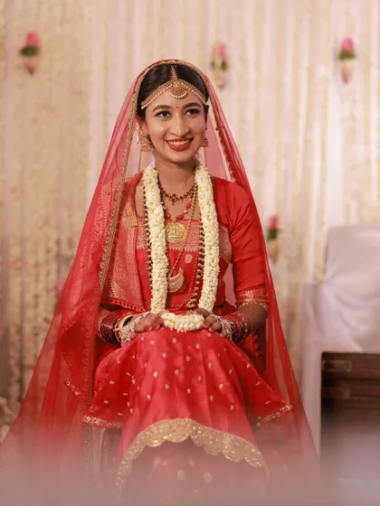 A seated portrait of the bride, her smile lighting up the frame. Her makeup is perfect for the occasion.
