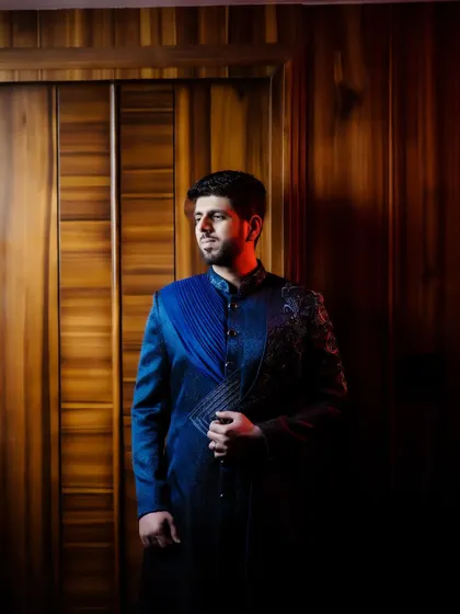A dramatic, low-light portrait of the groom in his stylish reception sherwani.