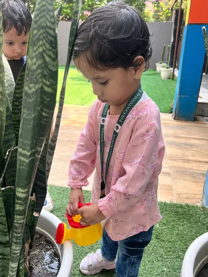 This little girl is gently watering a snake plant. We teach our children to be gentle and caring towards all living things, fostering a sense of empathy.