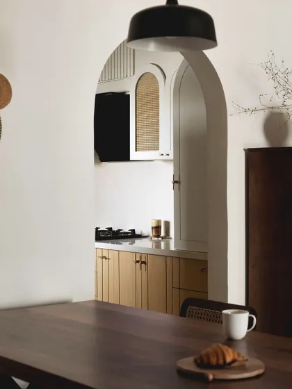 An archway bridges the living area and the kitchen, mirroring the arches on the kitchen cabinets. This simple detail enhances the spatial flow and extends the design language across the home.