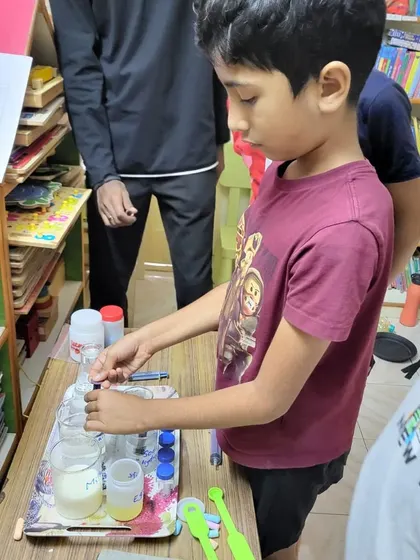 A student focuses intently on adding a substance to a beaker during a chemistry workshop.