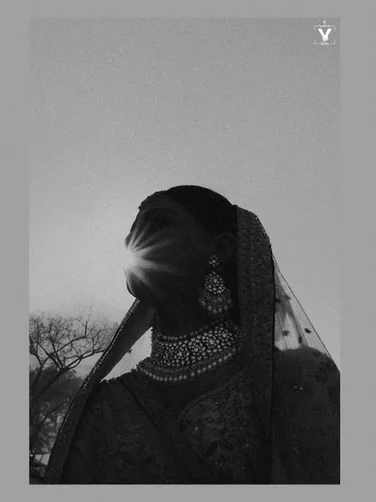 An artistic black and white silhouette of the bride against the sun. The sunburst effect creates a powerful and dramatic image that is both abstract and deeply emotional.