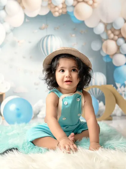 A dreamy blue and white balloon setup for a special first birthday. This little boy in his hat and overalls looks so adorable in his sky-themed celebration.