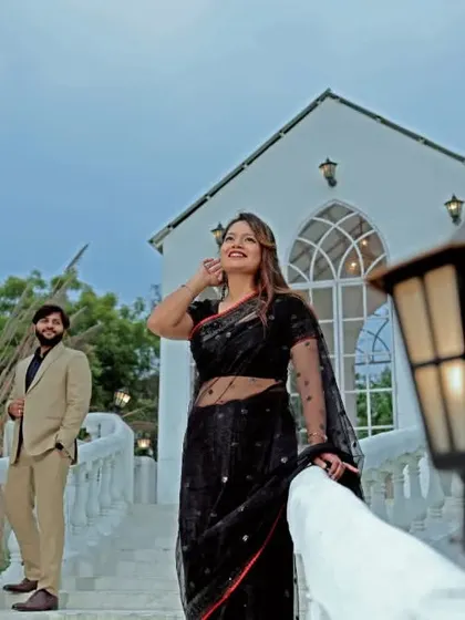 An elegant pre-wedding portrait on a white bridge. The bride's black saree stands out beautifully against the classic architecture, creating a timeless and sophisticated look.