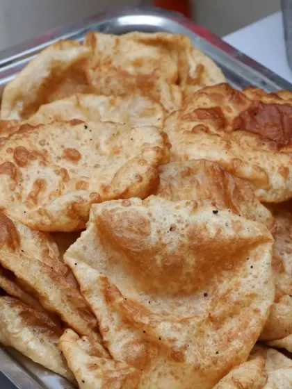 A tray of freshly fried, fluffy pooris, a classic Indian bread that pairs perfectly with our vegetable curries.