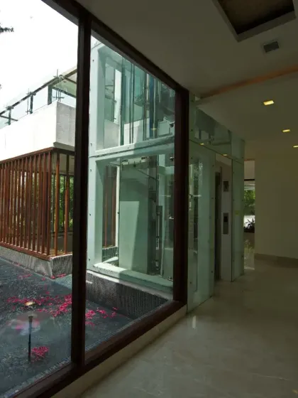 In the Sachdeva Farmhouse, a glass lift is set beside a waterbody, blurring the boundary between indoors and outdoors. This feature serves as both a focal point and a connector, bringing light and reflections into the home.