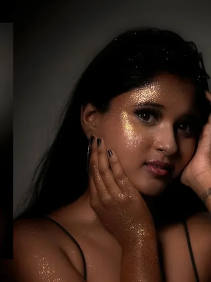A close-up portrait where the model is covered in gold glitter, creating a magical, stardust effect that glows in the light.