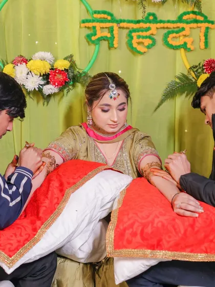 A behind-the-scenes shot of the Mehndi artist at work, capturing the process of the tradition.