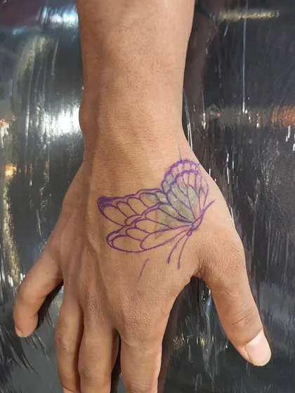 Before: A simple, faded outline of a butterfly on the hand, ready for a colorful transformation.