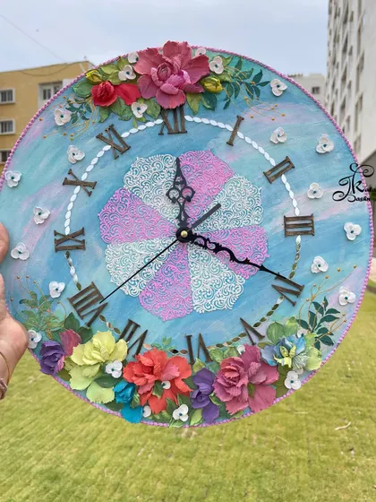 This 12-inch wall clock was a custom piece designed to match a client's room colors. The blue and pink theme is carried through from the base to the central filigree pattern and the surrounding floral arrangement.