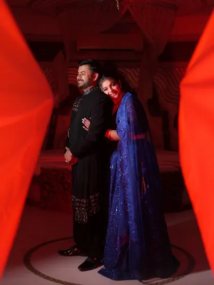 An artistic and intimate portrait of the couple, framed by red curtains, creating a dramatic and passionate feel for their reception look.
