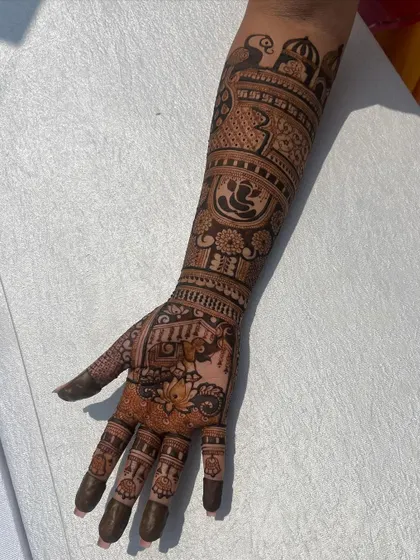 A single-hand view of a detailed bridal design, featuring Ganesha, peacocks, and domes.