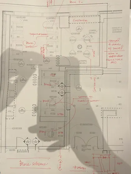 A hand-marked architectural plan, showing the shadow of a hand, symbolizing the human touch and creative thought behind every design.